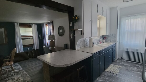 A compact kitchen with a central island, built-in cabinets, and a window with curtains. - Great Location - 3 miles to Cedar Point Park, 2.8 miles to CP Sports  Force Park (Sandusky)