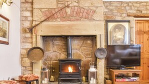 A stone fireplace with a TV on a wooden stand beside it.