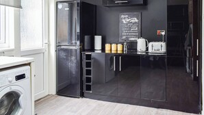 Una cucina funzionale con frigorifero, lavatrice e lavagna con una frase motivazionale.