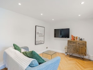 A modern living room with a sofa, a television, a cabinet, and a framed quote on the wall.