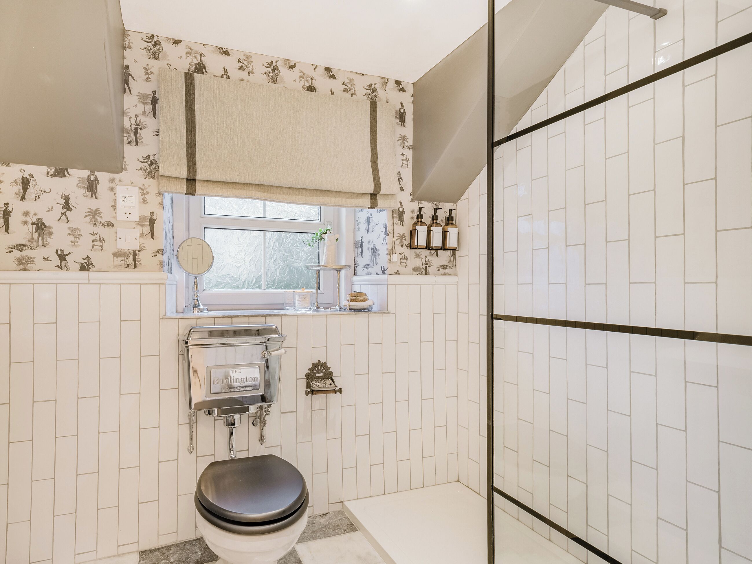 Une salle de bain comprenant des toilettes, une fenêtre, un miroir et un espace douche.