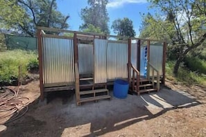 Una obra en construcción con estructura de madera, paneles de metal corrugado y un barril azul.