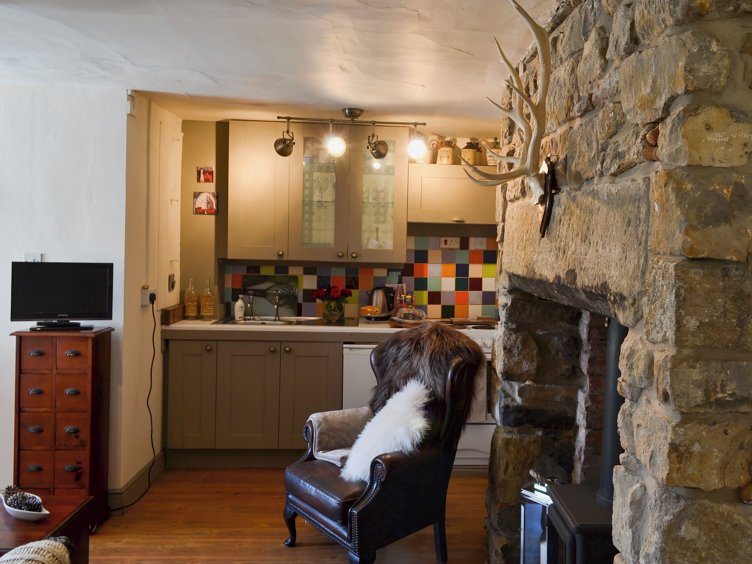 A cozy living room with a fireplace, a television, and a dining area with a tiled backsplash.