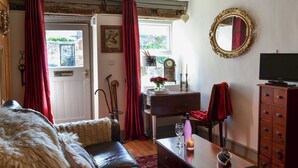 A cozy living room with a leather sofa, a wooden coffee table, and a television on a wooden cabinet.