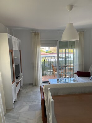 Ein Schlafzimmer mit Bett, Fernseher und einem Balkon mit Tisch und Stühlen.
