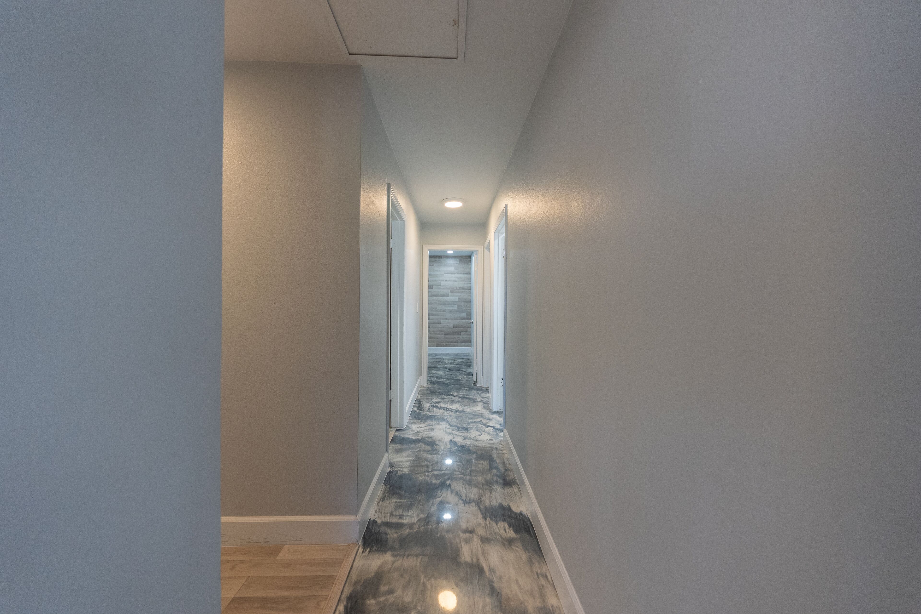 A hallway with a glossy, reflective floor and white walls.