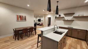 Een moderne keuken met een centraal eiland, een houten eettafel en stoelen.