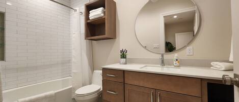 A modern bathroom with white subway tiles, a wooden vanity, a large mirror, and a shower area.