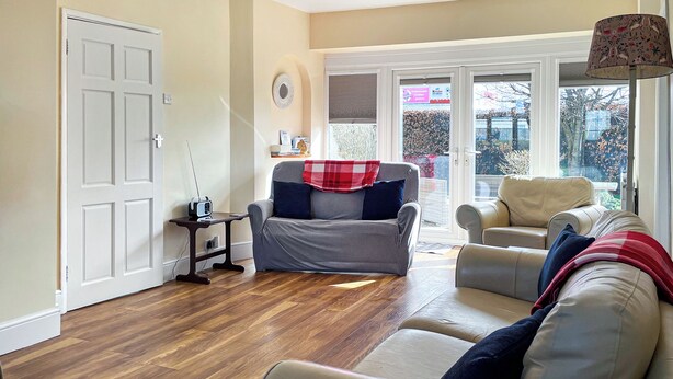 A living room with two sofas, a small table, and a door. - 4 bedroom accommodation in Hunstanton (Hunstanton)
