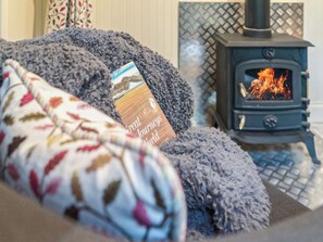A cozy room with a fireplace, a blanket, and a book titled 'Great Journeys World'. - 1 bedroom accommodation in Melton Constable (Melton Constable)