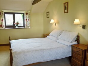 A bedroom with a bed, two bedside lamps, a nightstand, a dresser, a window with curtains, and a framed picture on the wall. - 3 bedroom accommodation in Dunterton, near Tavistock (Dunterton, near Tavistock)