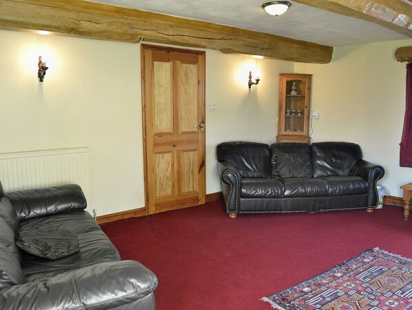 A living room with a dark leather sofa, a wooden door, and a cabinet with a light fixture.
