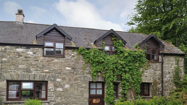 A stone building with multiple windows and a door, surrounded by greenery. - 3 bedroom accommodation in Dunterton, near Tavistock (Dunterton, near Tavistock)