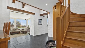 Un interior amplio con una escalera, una zona de comedor y vistas por un gran ventanal.