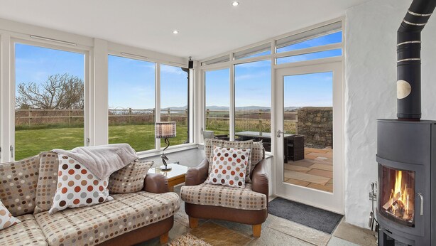 Una sala de estar acogedora con chimenea, ventanas amplias y vistas al campo.