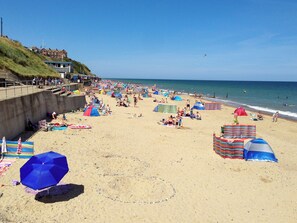 Une plage avec des tentes, des parasols et des gens.