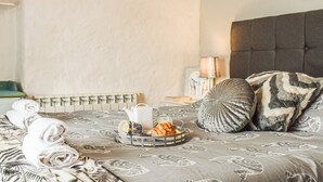 Un lit bien fait, recouvert d’une couvre-lit à motifs, une table de chevet avec une lampe et un tableau accroché au mur.