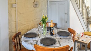 Une table à manger dressée avec des assiettes, des couverts et un vase de fleurs.