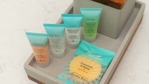 A tray with various body care products including a body bar, conditioner, lotion, and shampoo.