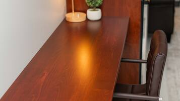 A wooden conference table with a modern lamp, a potted plant, and leather chairs.