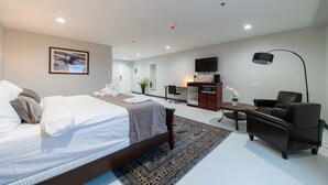 A modern hotel room with a large bed, a desk, a chair, and a TV.