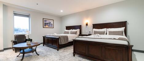 A hotel room with two beds, a desk, and a chair.