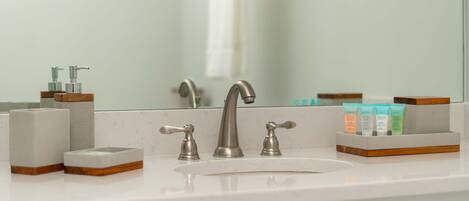 Un lavamanos de baño con un grifo moderno, un dispensador de jabón y un jabonera.