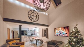 Ein Wohnzimmer mit Essbereich, Kamin, Weihnachtstannenbaum und Wandfernseher.