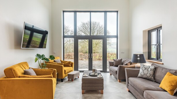 Ein modernes Wohnzimmer mit großem Fenster, Flachbildfernseher und zwei Sofas.