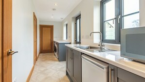 Ein schmaler Flur führt zu einer Küche mit Waschmaschine, Spüle und Fenster.