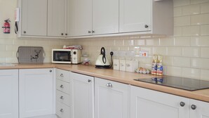 A kitchen with white cabinets, a microwave, a kettle, and a toaster. There are also jars labeled 'Sugar,' 'Tea,' and 'Coffee.' - 2 bedroom accommodation in Llanfachraeth, near Holyhead (Llanfachraeth, near Holyhead)