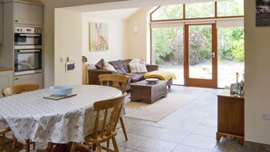 A dining area with a table, chairs, a sofa, and a view through a glass door to the outdoors. - 2 bedroom accommodation in Llanfachraeth, near Holyhead (Llanfachraeth, near Holyhead)