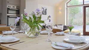 A dining table set with plates, glasses, and a vase of flowers. - 2 bedroom accommodation in Llanfachraeth, near Holyhead (Llanfachraeth, near Holyhead)