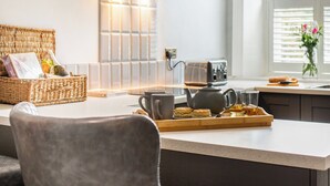 Eine moderne Küche mit Kochinsel, einem Korbwäschesessel, einem Toaster und einer Vase mit Blumen.