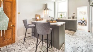 Eine moderne Küche mit einer zentralen Kochinsel, Barhocker und einer Holztür.