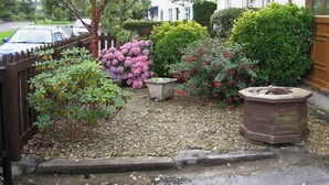 A residential garden with a gravel pathway, various shrubs, and a wooden fence. - 3 bedroom accommodation in Llansteffan (Llansteffan)