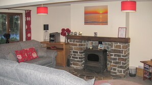 A living room with a fireplace, a sofa, and a coffee table. - 3 bedroom accommodation in Llansteffan (Llansteffan)