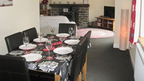A dining area with a table set for four, a fireplace, and a television in the background. - 3 bedroom accommodation in Llansteffan (Llansteffan)