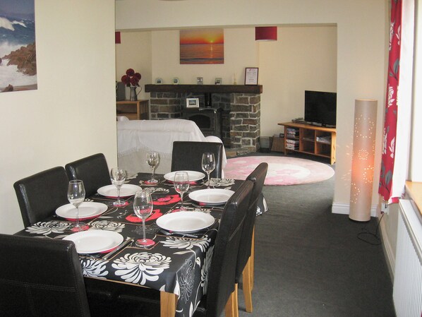 A dining area with a table set for four, a fireplace, and a television in the background.