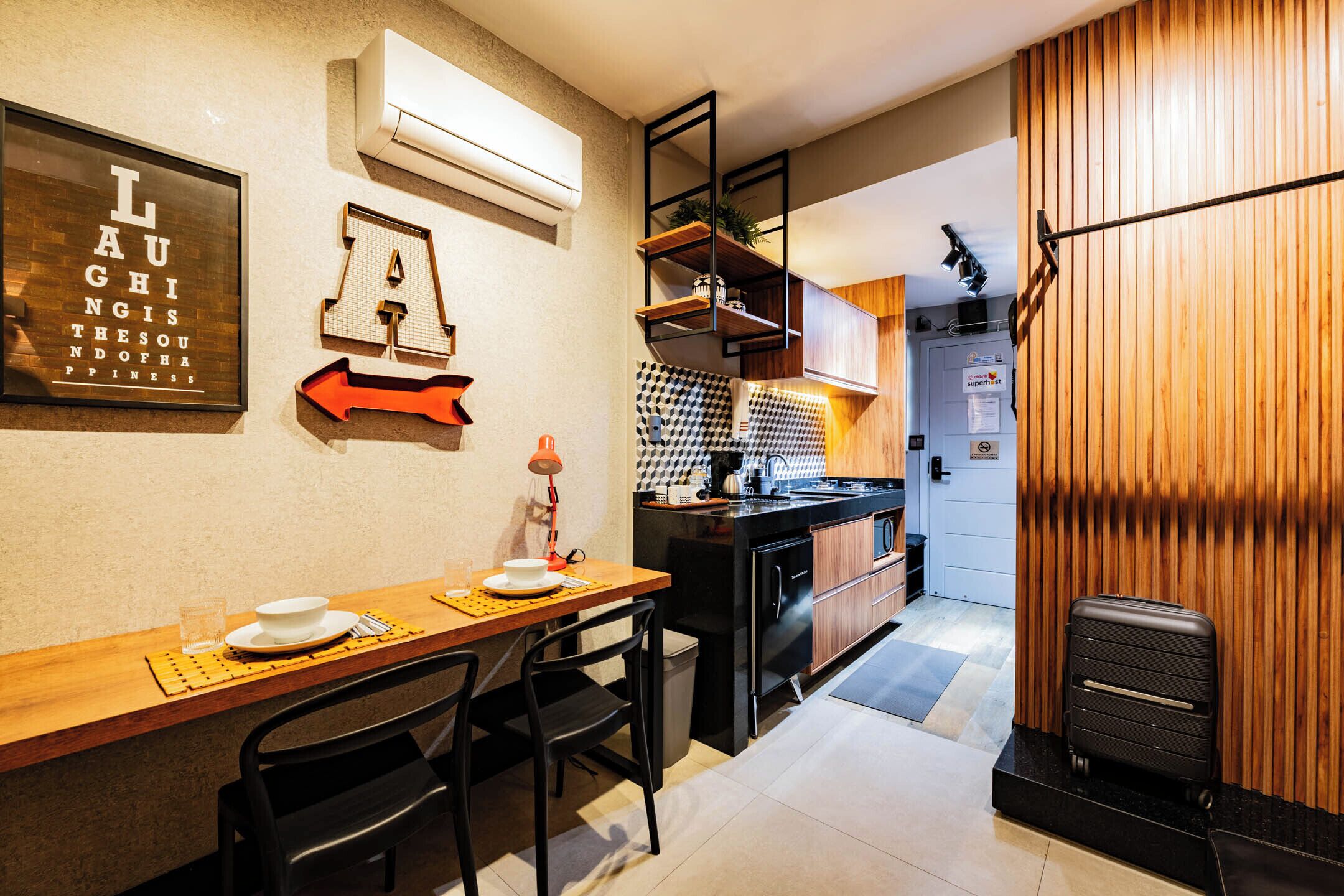 Een kleine keuken met een eethoek, een bar en een houten wand.