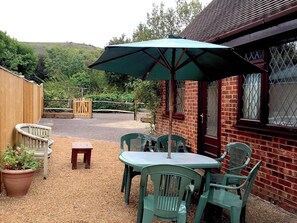A patio with a table and chairs, a wooden fence, and a brick building.