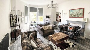 Un salon avec deux canapés, une table basse, une cheminée et un tapis en peau de vache.