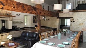 A dining area with a long table set for six, wooden chairs, and a black leather sofa. - Stunning, 4 ⭐️ relaxing, peaceful, private pool, fishing lake sleeps 18 Dordogne (Saint-Martin-de-Gurson)