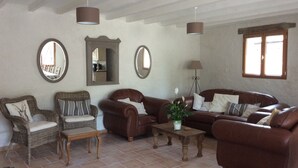 A living room with two sofas, a coffee table, and two armchairs. There are two mirrors on the wall, a floor lamp, and a window with blinds. - Stunning, 4 ⭐️ relaxing, peaceful, private pool, fishing lake sleeps 18 Dordogne (Saint-Martin-de-Gurson)