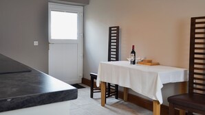Un comedor con una mesa lista para dos, una botella de vino y una silla.