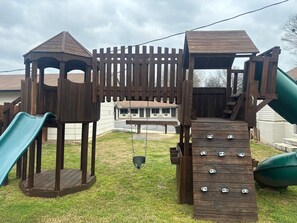 A wooden play structure with a slide and climbing elements. - Yellow Diamond Inn (Murfreesboro)