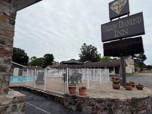 A hotel entrance with a sign reading 'Yellow Diamond Inn,' a fenced pool area, and a digital display board.