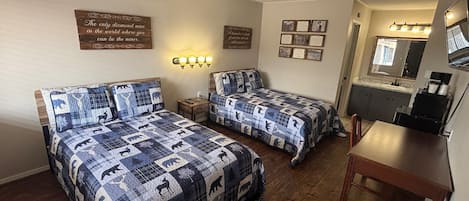 Una habitación con dos camas, un escritorio, un espejo y luces fijadas a la pared.