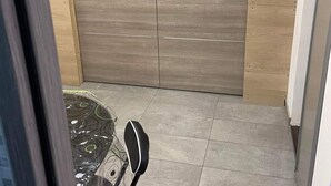 Una habitación con un armario de madera, una mesa con sillas y suelo de baldosas.