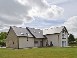 A modern building with a stone facade, a sloped roof, and a patio area with outdoor seating.
